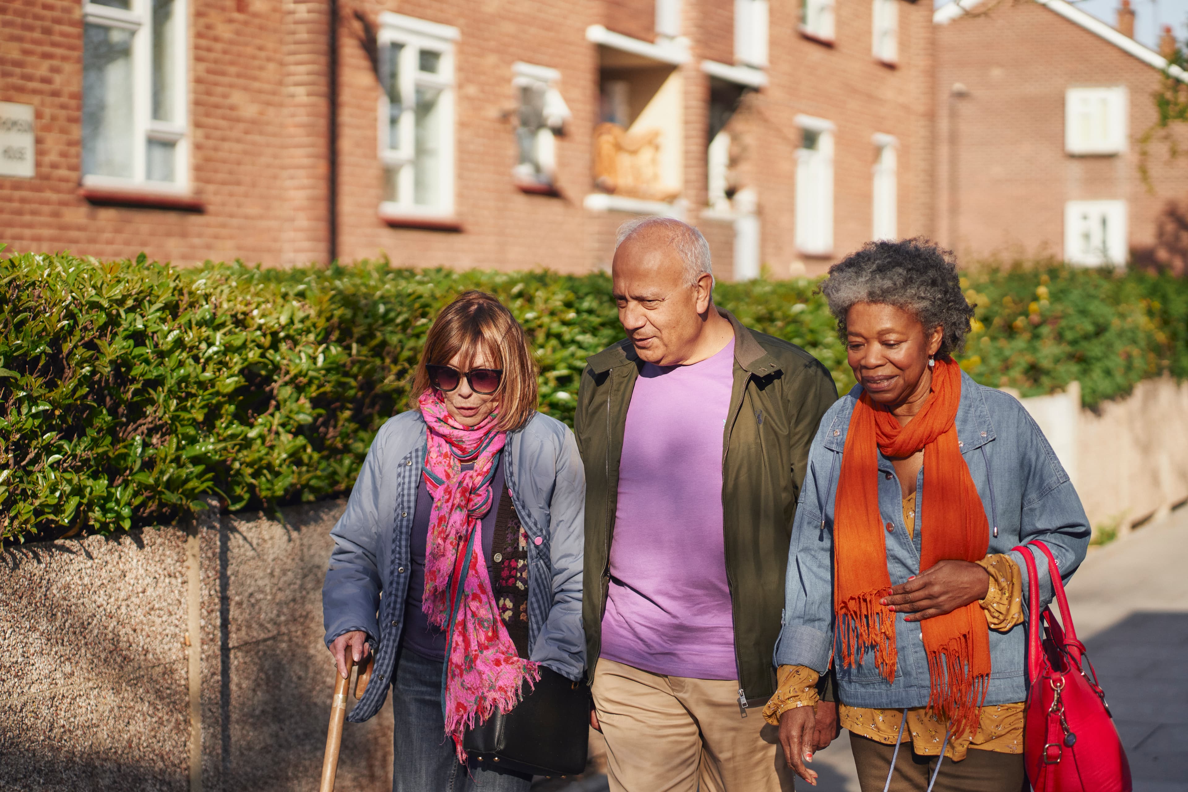 Three people walking down the street chatting to each other.