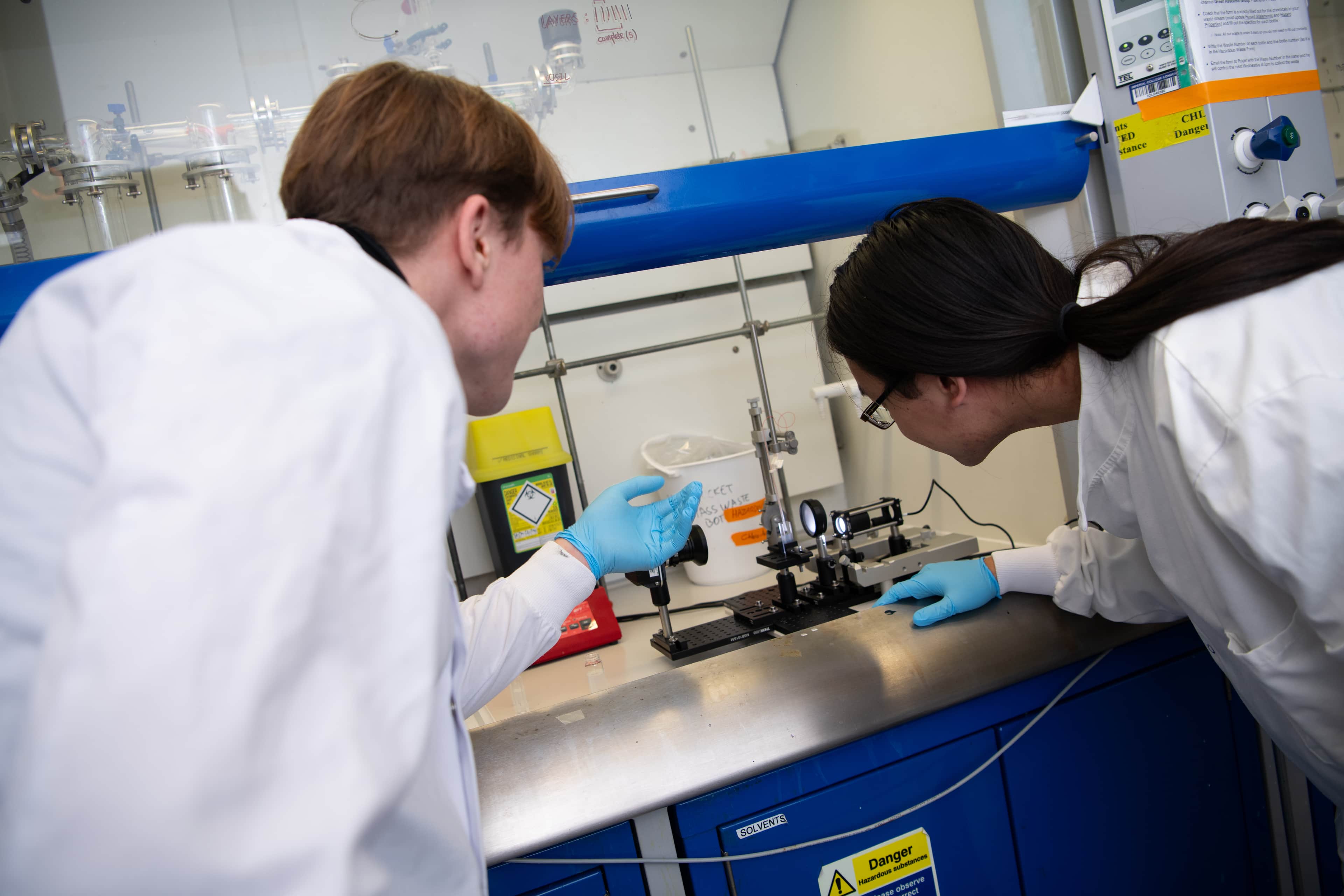 Two researchers looking in a fume hood.