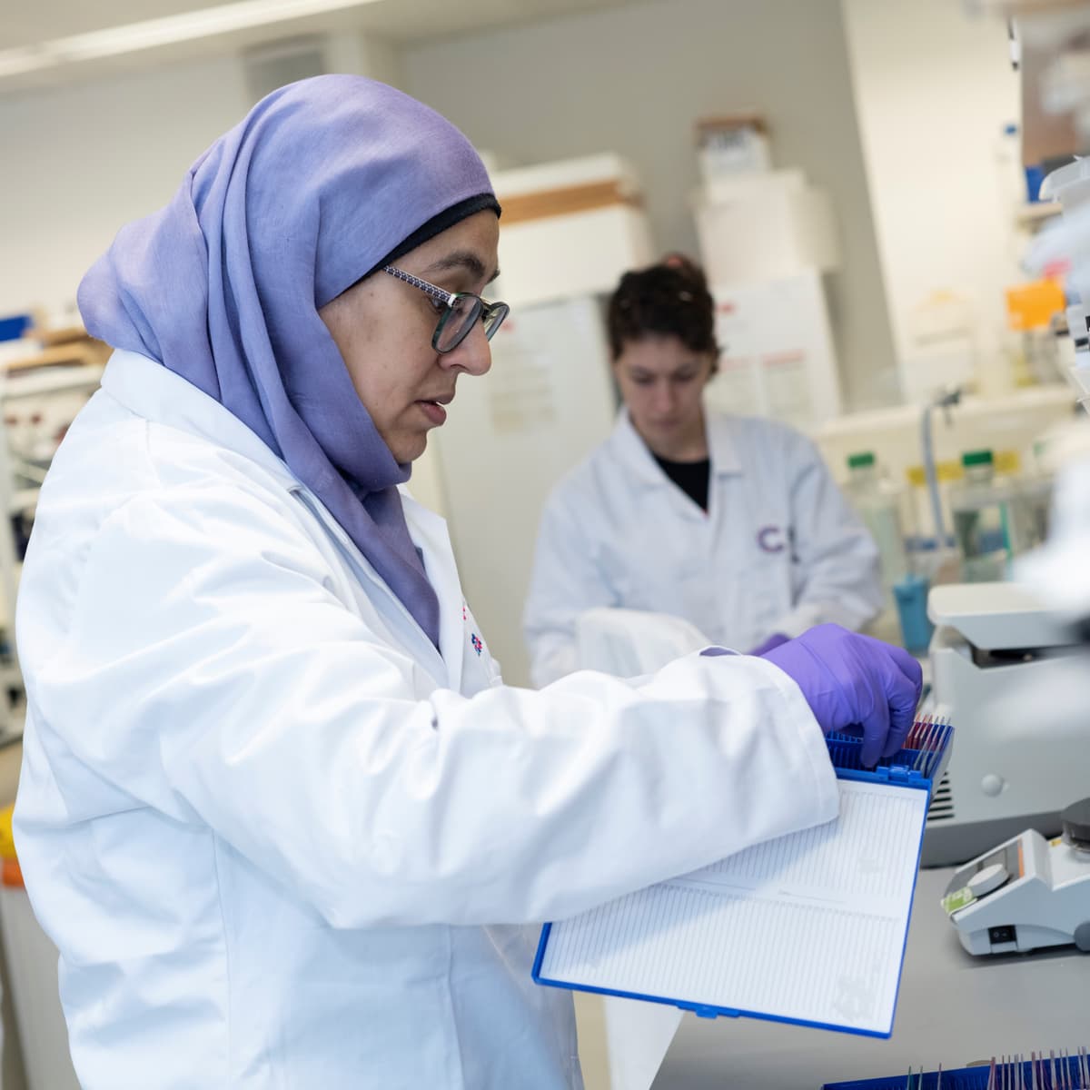 Image of a researcher with a white lab coat in a lab using equipment.