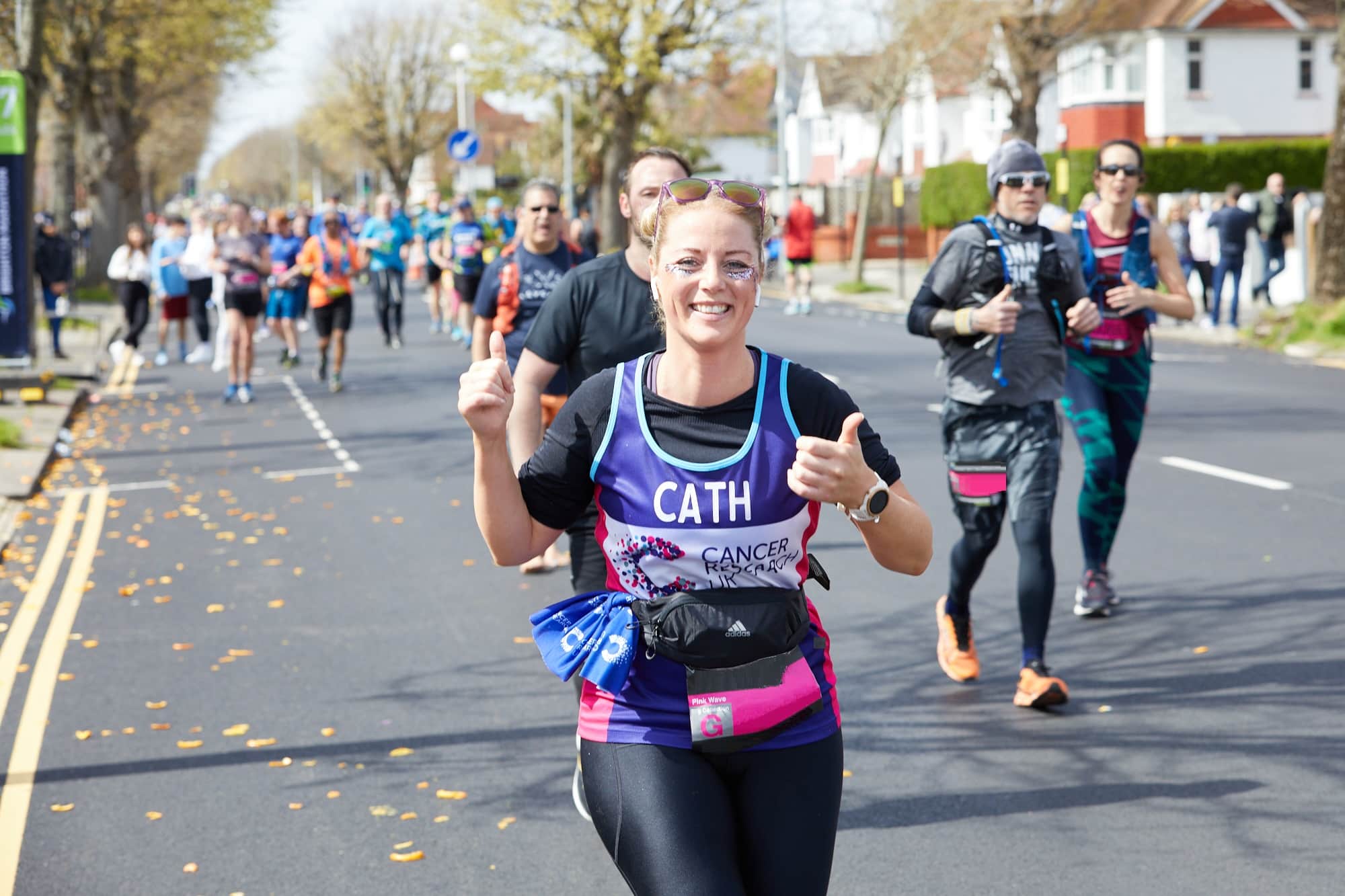 Woman wearing a CRUK T-shirt running and smiling during the Brighton marathon.