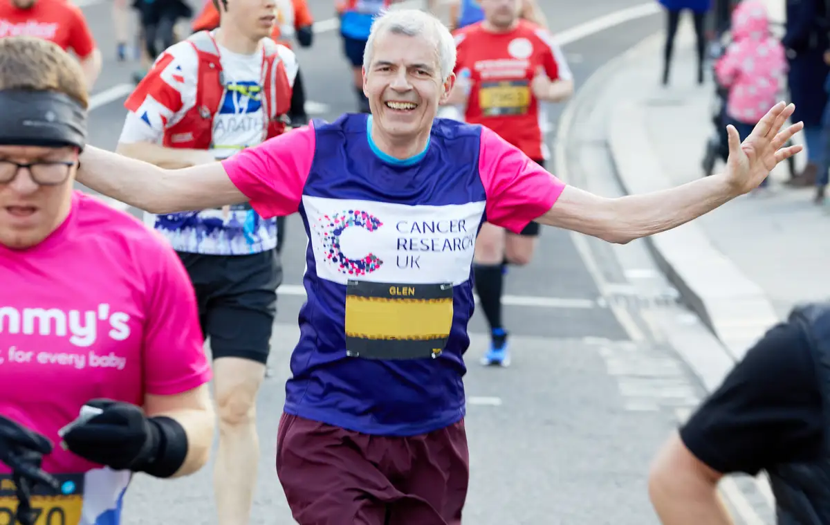 Runner wearing a CRUK top whilst holding his arms out wide.