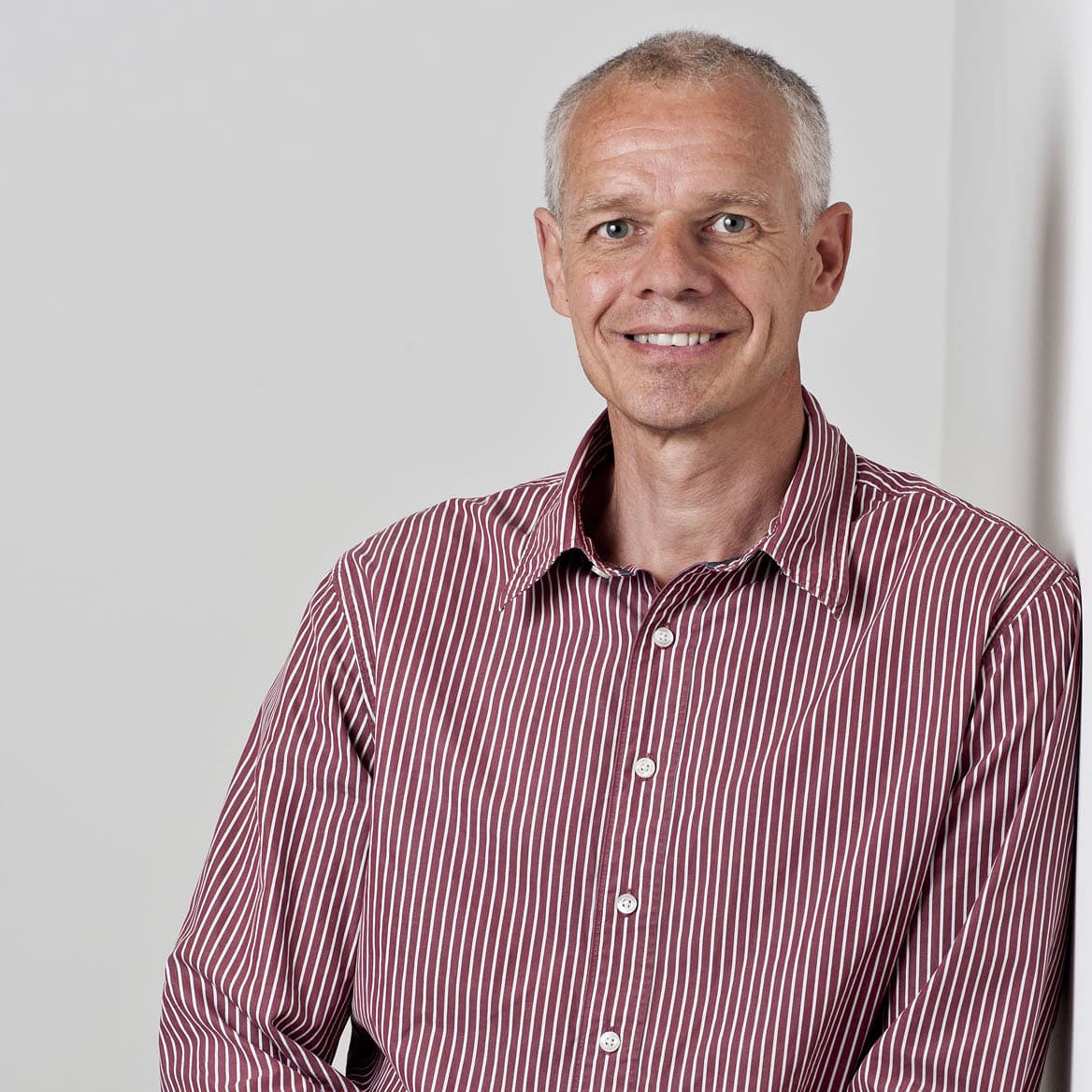 Image of Oliver, leaning against a wall and smiling to camera.
