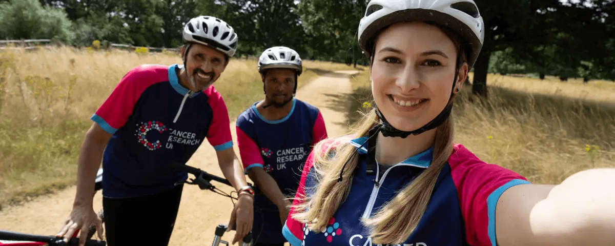A photo of three cyclists wearing Cancer Research UK t-shirts.