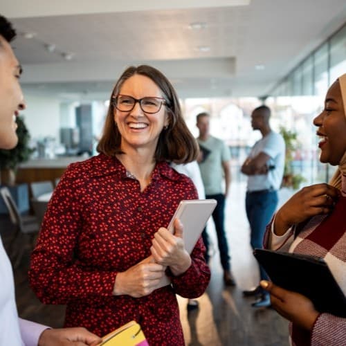 Three people are stood in an office having a pleasant discussion.