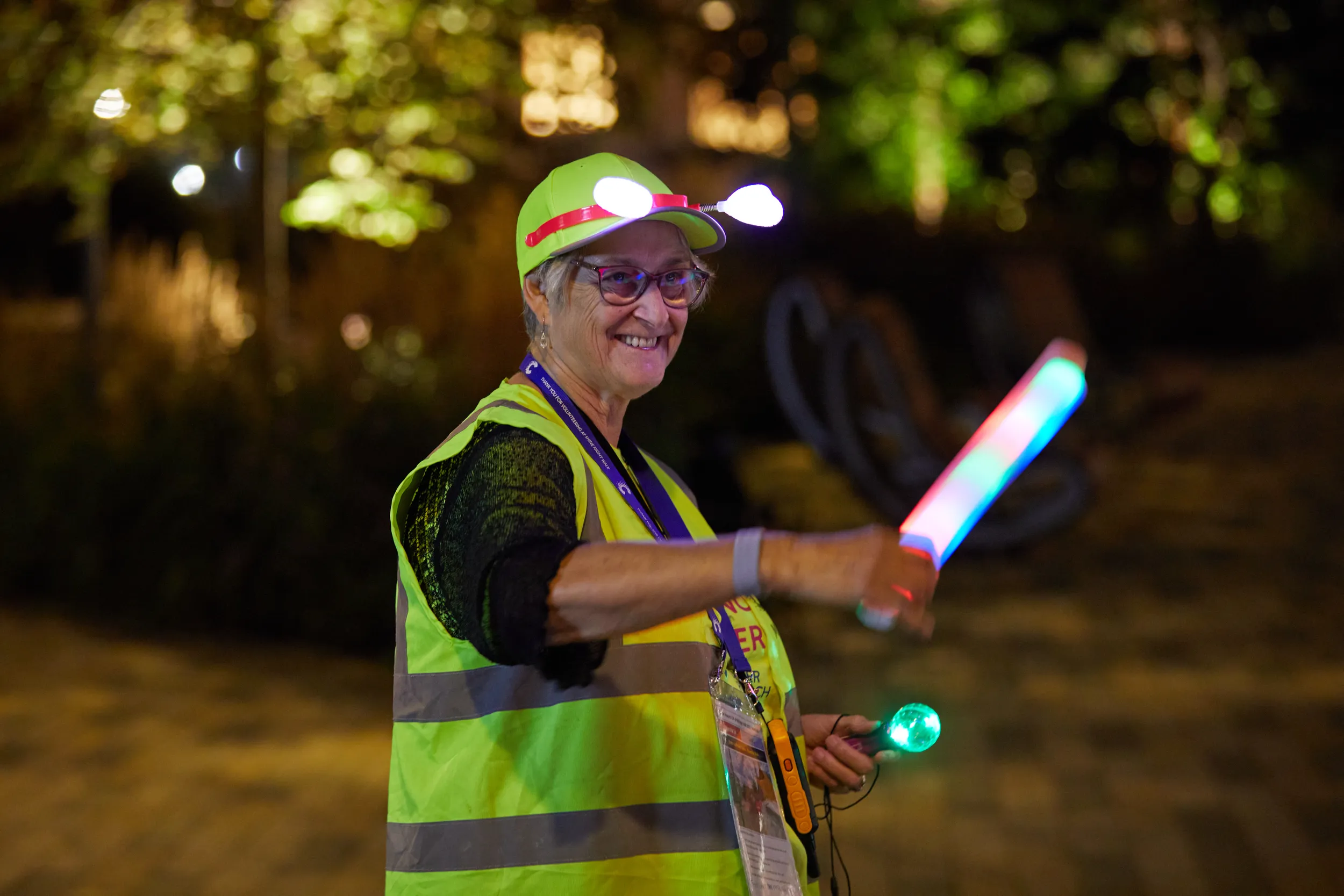 Image of a female volunteer at Shine Night Walk, directing people with a light.