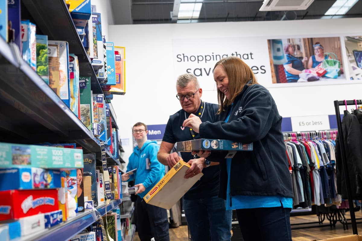 Photo of a person smiling dressing a mannequin in a shop window.