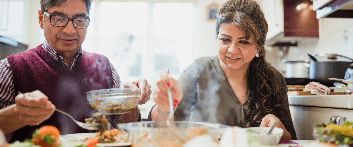 Mature couple are enjoying a homemade curry with salad at home..