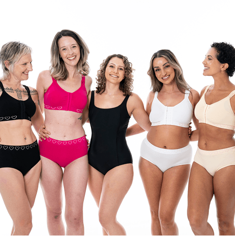 A photo of five women hugging and smiling.