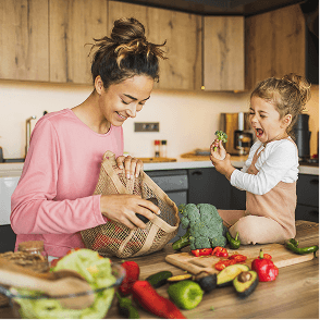 A photo of a mother with her toddler in a kitchen preparing food together.