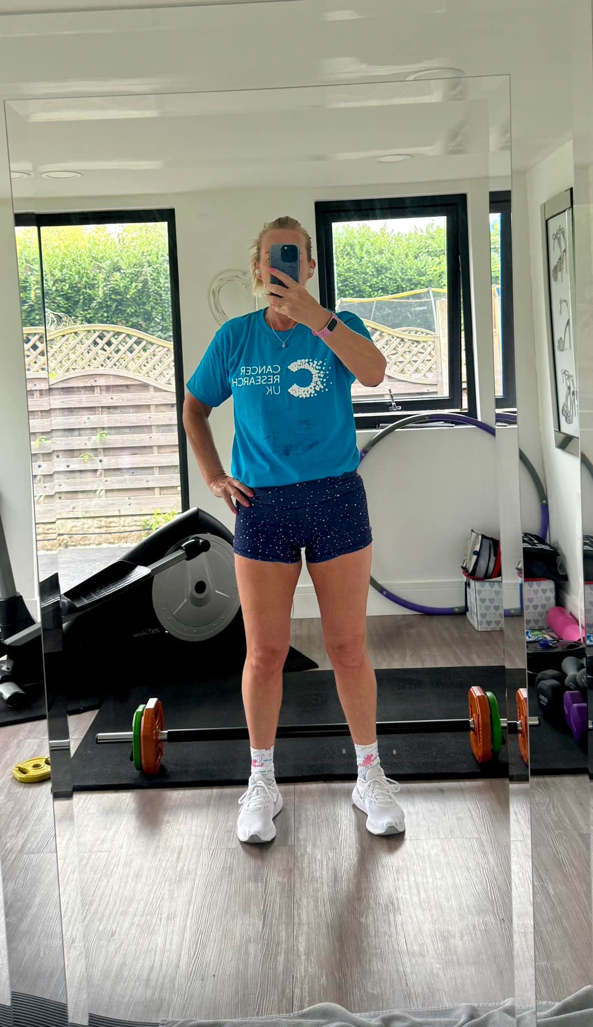 Picture of a women taking a selfie in a mirror wearing a Cancer Research UK t-shirt.