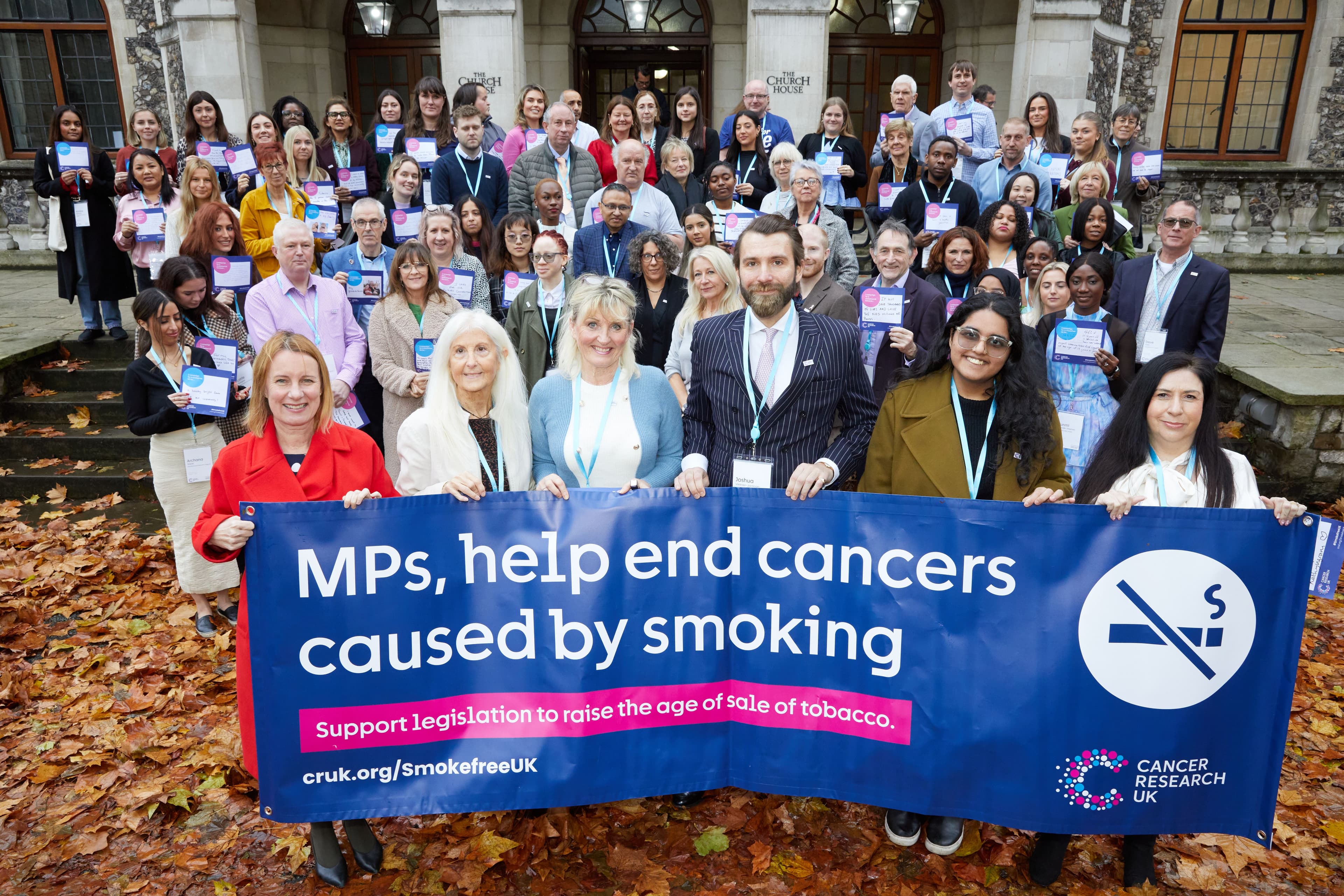 Campaigns Ambassadors holding a banner that reads MPs, help end cancers caused by smoking.