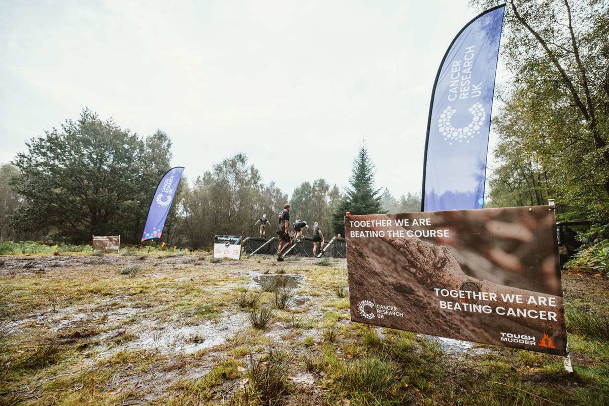 Image of field with Cancer Research UK banners at Tough Mudder event.
