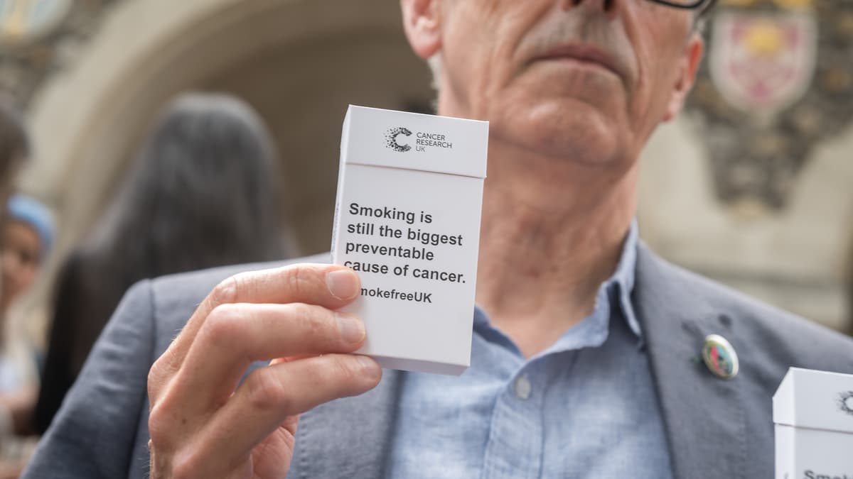 Older man holding a box of cigarettes.